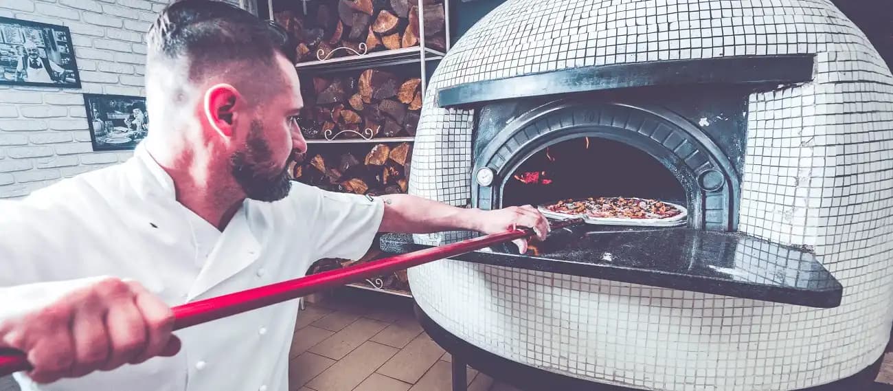 Pizza chef cooking in front of a wood-fired oven
