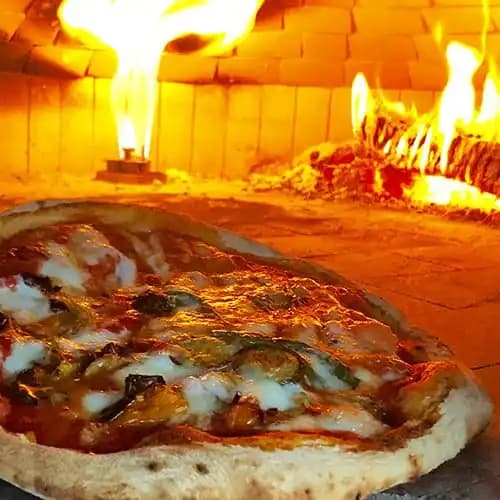Pizza baking with flame in oven